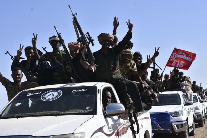 A truck with Sudan Shield Forces members and branded with the Sudan Shield Forces emblem at an unknown location. 
