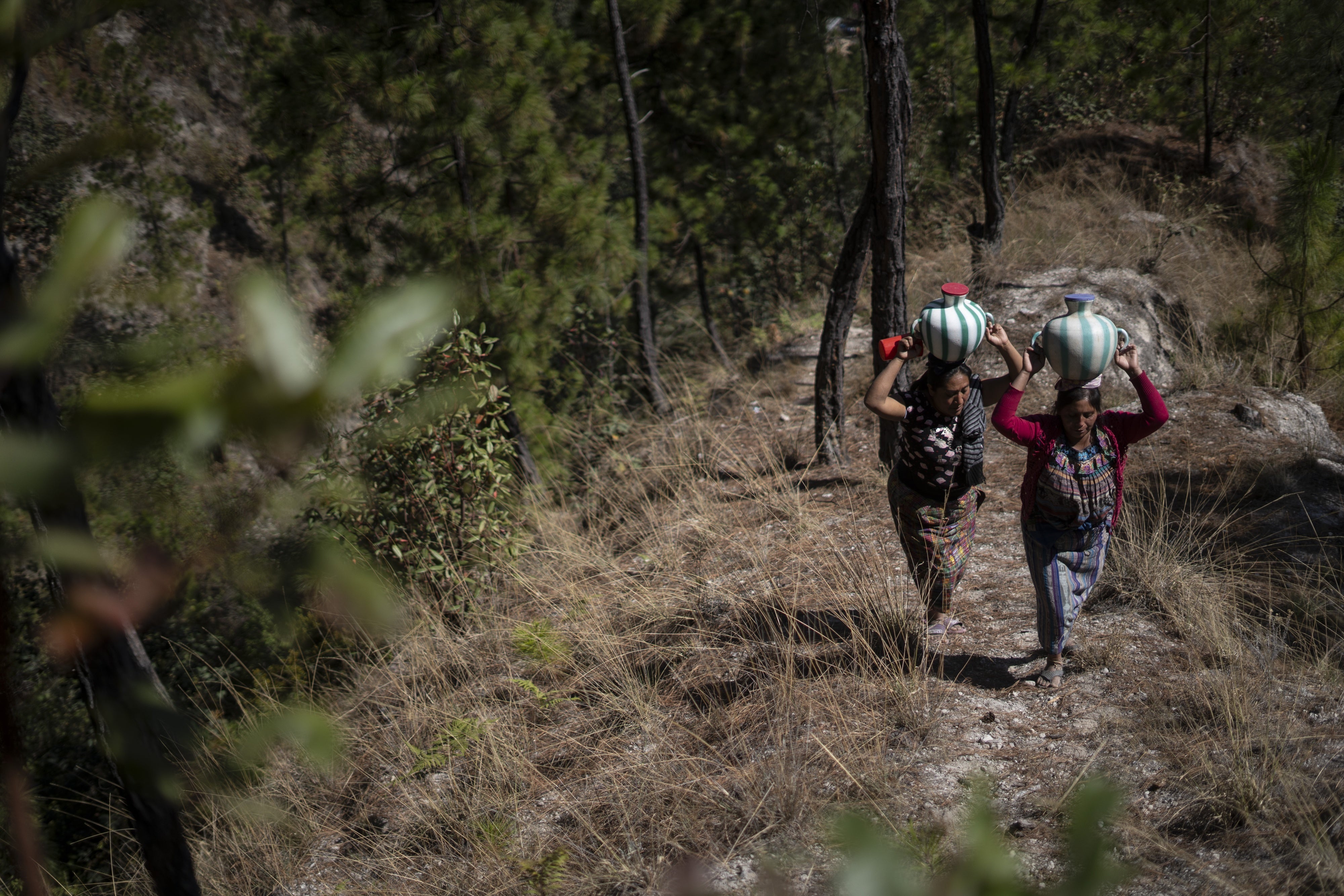 Two women in Santa María Chiquimula municipality, Totonicapán department, transport water home from a well. 