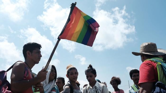A group of men and women march walk while holding rainbow pride flags