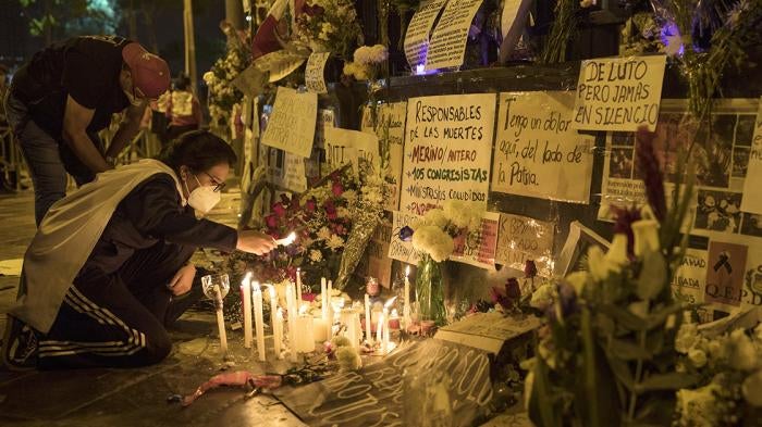 A woman lights a candle at a memorial for protesters who were injured or killed in Lima in November 2020, outside of Peru’s Congress building.