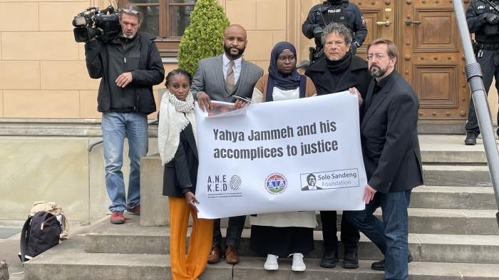 A group of people standing on steps hold a sign