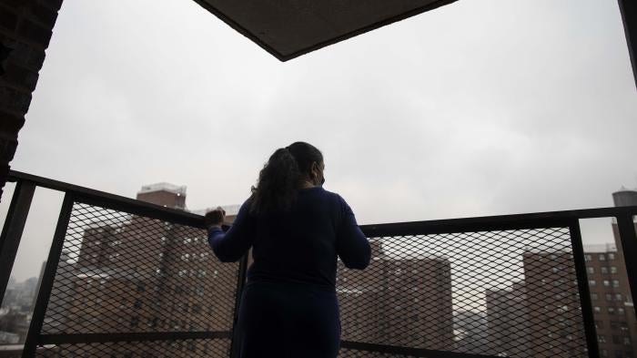 A woman looks out at a city from a patio