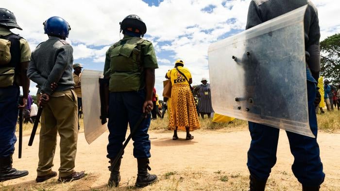 A line of police with riot shields stand in front of protestors