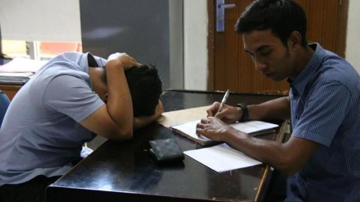 On March 29, 2018, vigilantes forcibly entered a private house in Aceh province and called the Sharia (Islamic law) police, who arrested two male college students for allegedly having sex. A police officer questions one of the men in the Sharia