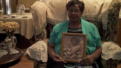 Ms. Frances Ford, executive director of Sowing Seeds of Hope, in her home in August 2018, holding a picture of her mother, who died from cervical cancer after being diagnosed in 1980. 