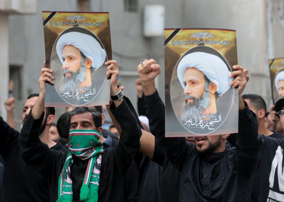Men hold placards bearing portraits of a prominent Shia Muslim cleric, Nimr al-Nimr, whose execution sparked demonstrations in 2016 by the country's minority Shia citizens against systematic governmental discrimination. Some of the alleged child offenders currently on trial were accused of attending similar protests. 