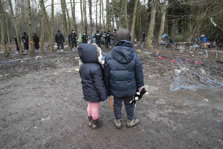 Zwei Kinder beobachten, wie die Polizei ihr Zelt bei der Räumung eines Migrantenlagers in Grande-Synthe, Nordfrankreich, am 21. Januar 2021 beschlagnahmt.