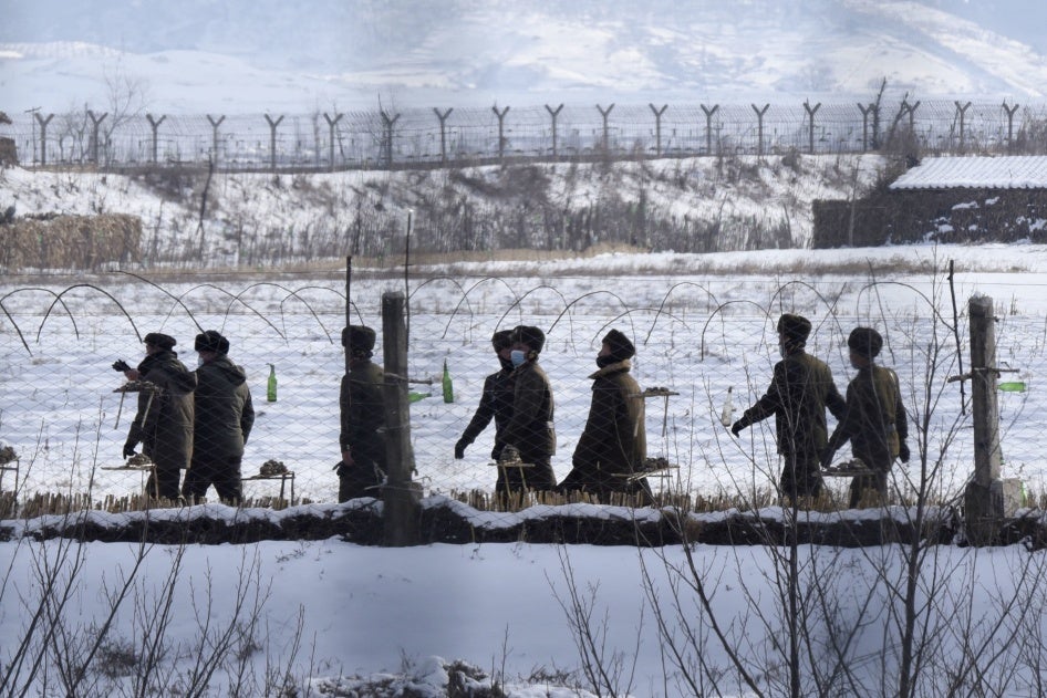 Uniformed border guards patrol next to a fence