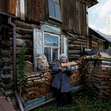 A pensioner carries logs in the courtyard of her wooden house where she opened a private museum of the old quarter.