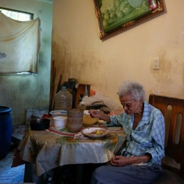 An older woman eats alone in her home