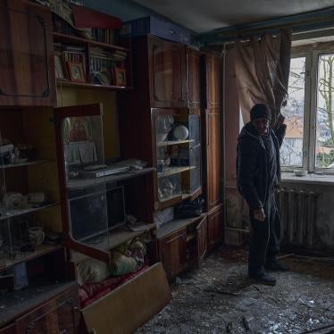 A man looks at shards of glass on his apartment floor 