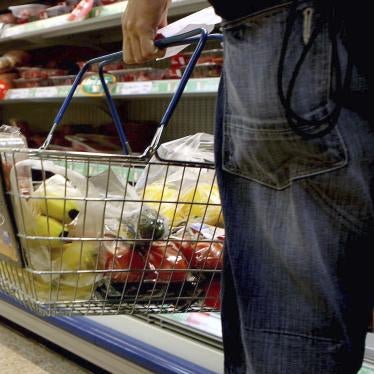 A person holding a shopping basket in a supermarket.
