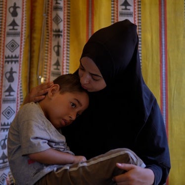 A woman holds her young son in her lap