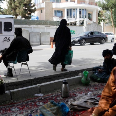 An Afghan woman walks among Taliban soldiers at a checkpoint in Kabul, Afghanistan, July 6, 2023. 