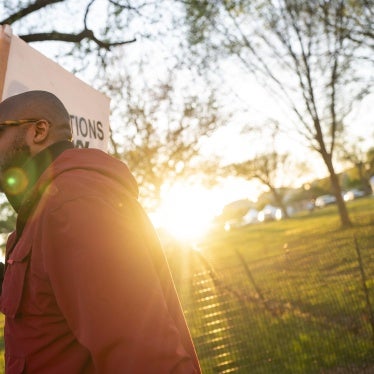 A man holding a sign that reads "Reparations Now"