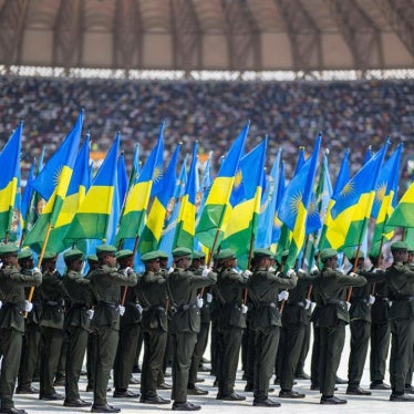 Members of the Rwanda Defence Forces march while holding Rwanda flags in a stadium