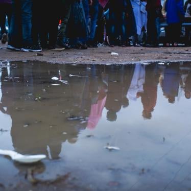 Les migrants à Calais se rassemblent sous la pluie pour une distribution de vêtements dans une zone industrielle à la périphérie de Calais, en France.