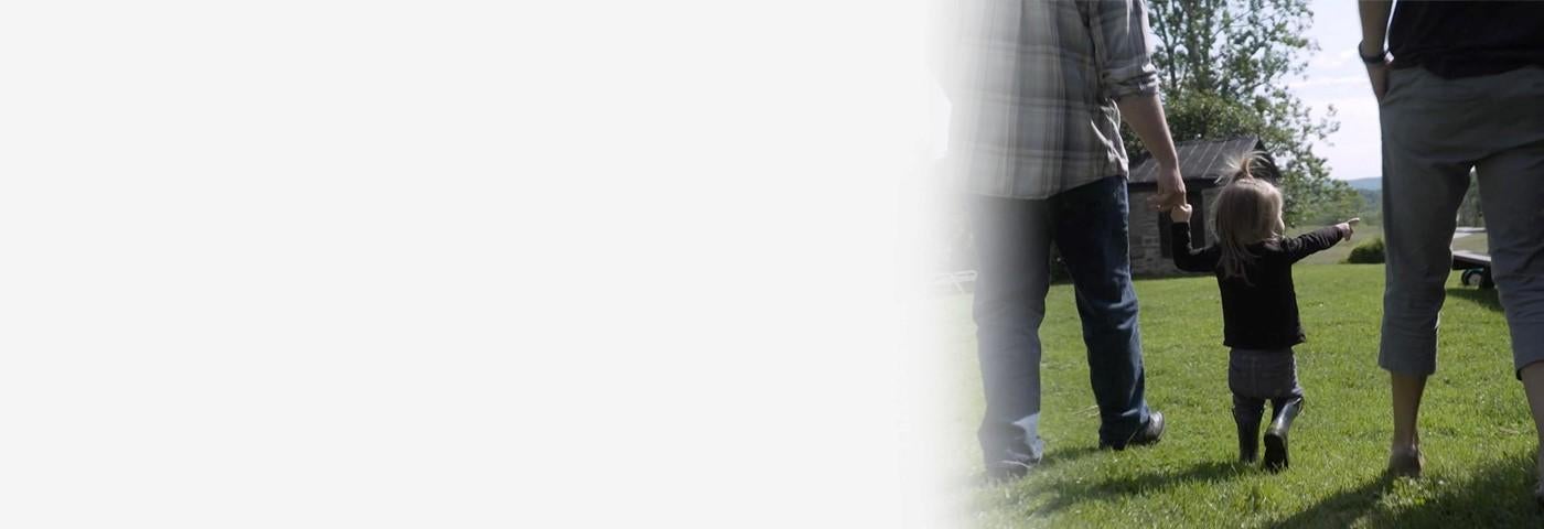 A two-and-a-half-year old born with intersex traits walks with her parents in their garden. The parents have decided to defer all medically unnecessary surgeries until their child can decide for herself.